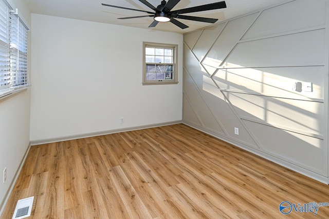 unfurnished room with light wood-style floors, ceiling fan, visible vents, and baseboards