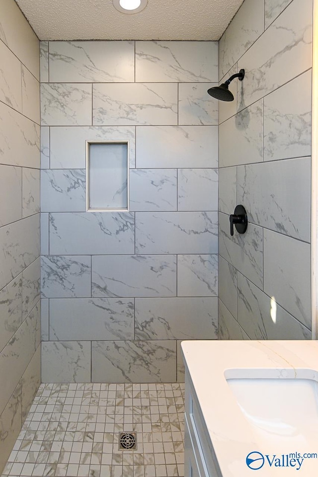 bathroom featuring a sink, a tile shower, and a textured ceiling