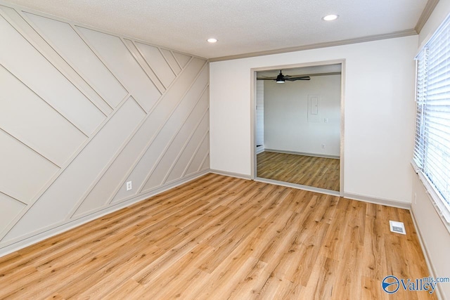 unfurnished bedroom with baseboards, visible vents, ornamental molding, a textured ceiling, and light wood-type flooring