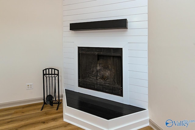 interior details featuring a fireplace, baseboards, and wood finished floors