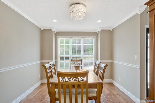 dining area featuring baseboards, light wood-style flooring, ornamental molding, and a chandelier