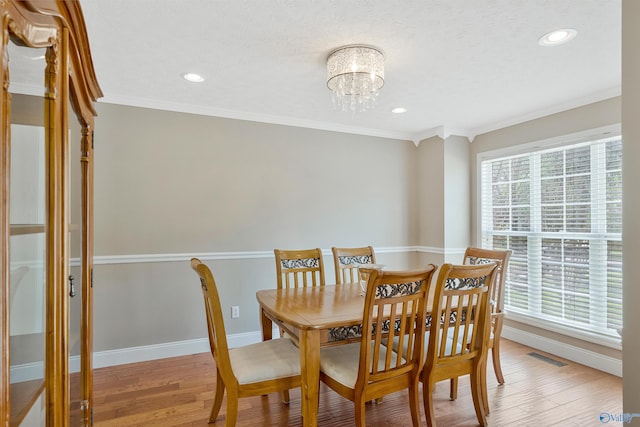 dining area featuring visible vents, a chandelier, light wood-style floors, and crown molding