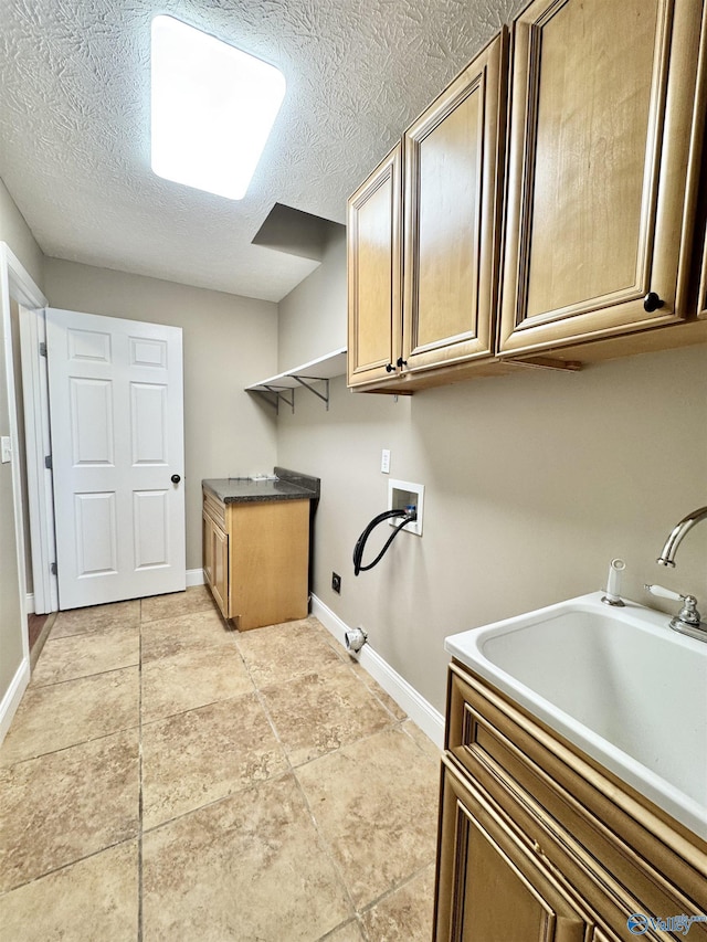 clothes washing area featuring hookup for a washing machine, baseboards, a textured ceiling, a sink, and cabinet space