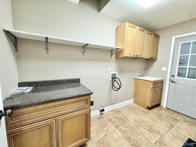 laundry room featuring baseboards, a textured ceiling, a sink, cabinet space, and washer hookup