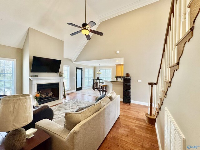 living room with a fireplace with flush hearth, baseboards, light wood finished floors, visible vents, and a ceiling fan
