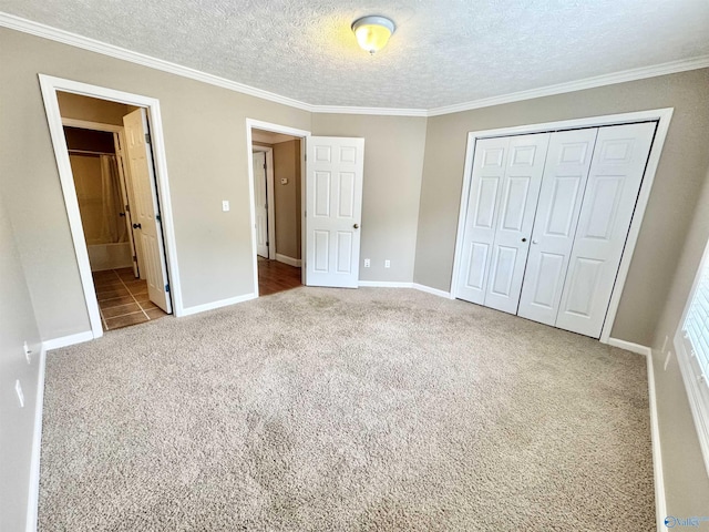 unfurnished bedroom with ornamental molding, carpet, baseboards, a textured ceiling, and a closet