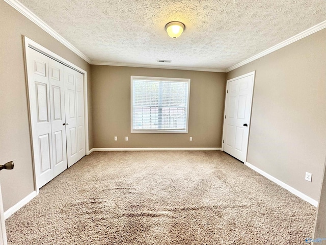 unfurnished bedroom featuring a closet, carpet floors, baseboards, visible vents, and ornamental molding