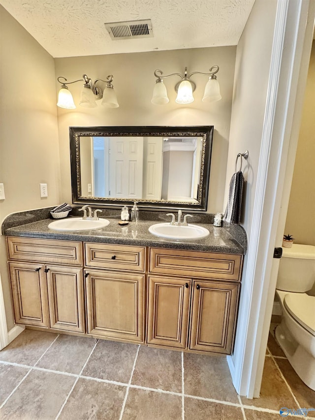 full bath featuring toilet, a sink, a textured ceiling, and visible vents