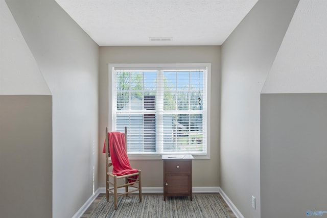 sitting room featuring baseboards, a textured ceiling, visible vents, and wood finished floors