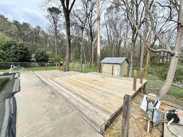 wooden terrace featuring an outdoor structure, a shed, and fence