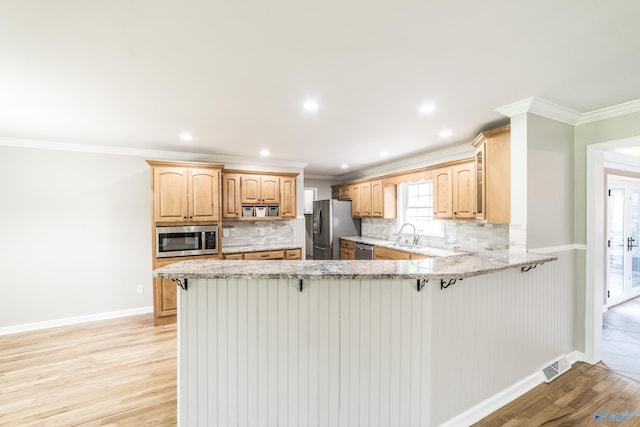 2600 Gawain Rd SE, Huntsville, AL 35803 - kitchen with appliances with stainless steel finishes, a peninsula, light wood-type flooring, decorative backsplash, and a breakfast bar