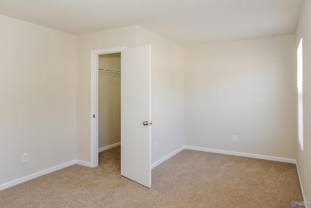 unfurnished bedroom with a closet, a walk in closet, and light carpet