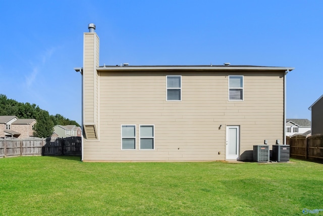 back of property with a yard and central AC