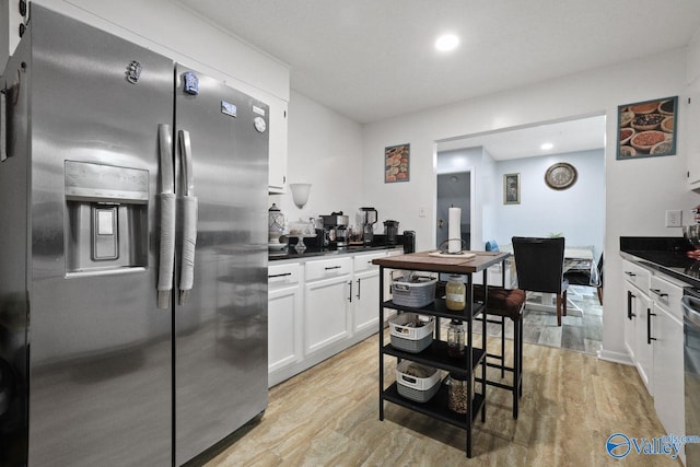 kitchen with light wood-type flooring, white cabinets, recessed lighting, stainless steel refrigerator with ice dispenser, and dark countertops