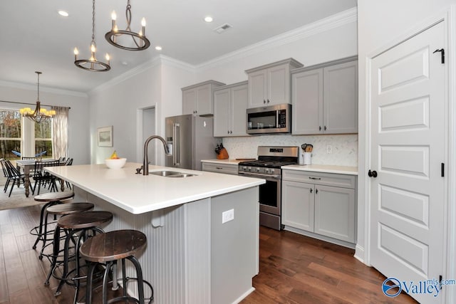 kitchen with visible vents, a breakfast bar area, gray cabinets, stainless steel appliances, and a chandelier