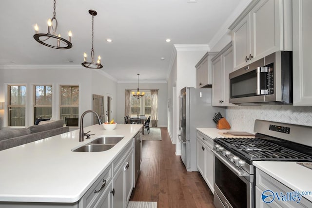 kitchen with tasteful backsplash, open floor plan, stainless steel appliances, a chandelier, and a sink