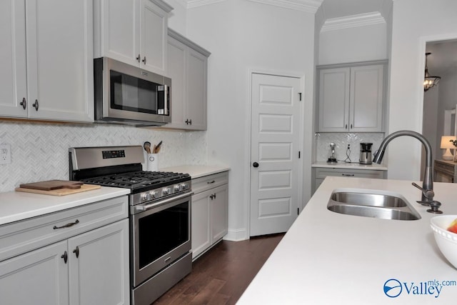 kitchen featuring stainless steel appliances, a sink, light countertops, and crown molding