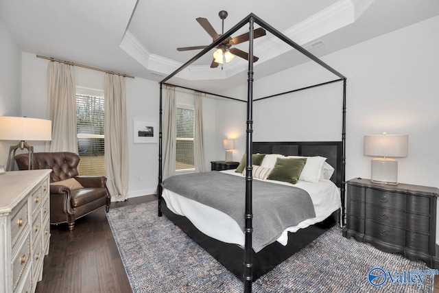 bedroom featuring ceiling fan, dark wood-type flooring, visible vents, ornamental molding, and a tray ceiling