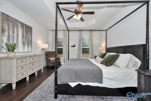 bedroom with ornamental molding, a tray ceiling, ceiling fan, and wood finished floors