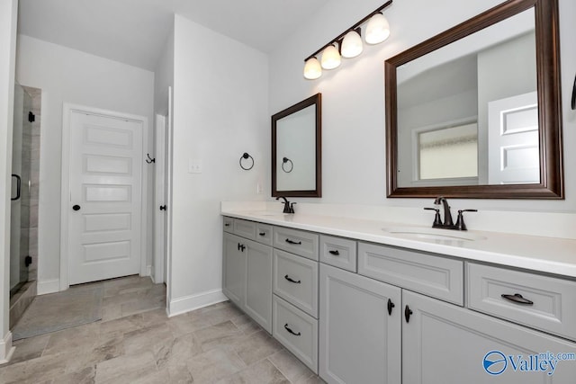 full bath featuring double vanity, a stall shower, baseboards, and a sink