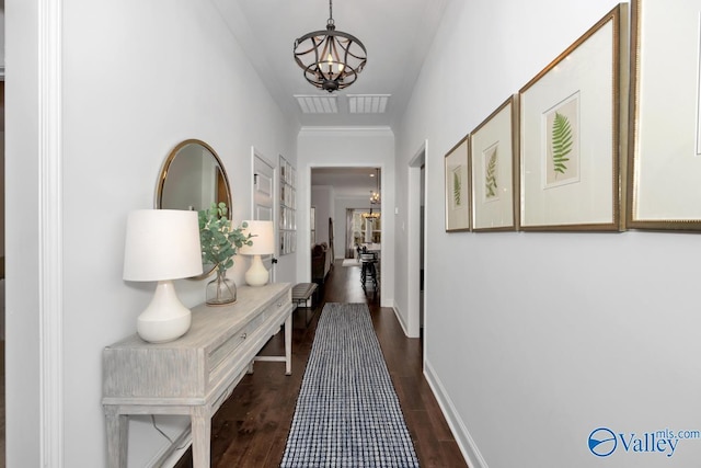 corridor with dark wood finished floors, baseboards, and an inviting chandelier