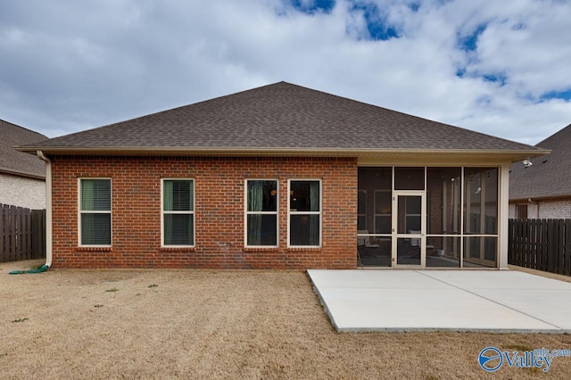 rear view of house with a sunroom, a patio area, fence, and brick siding