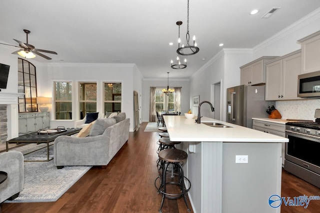 kitchen with stainless steel appliances, visible vents, open floor plan, a sink, and a kitchen breakfast bar