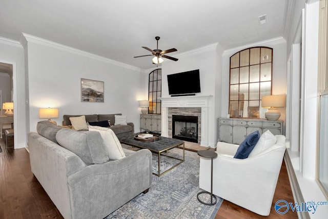 living room featuring ornamental molding, dark wood finished floors, and a stone fireplace