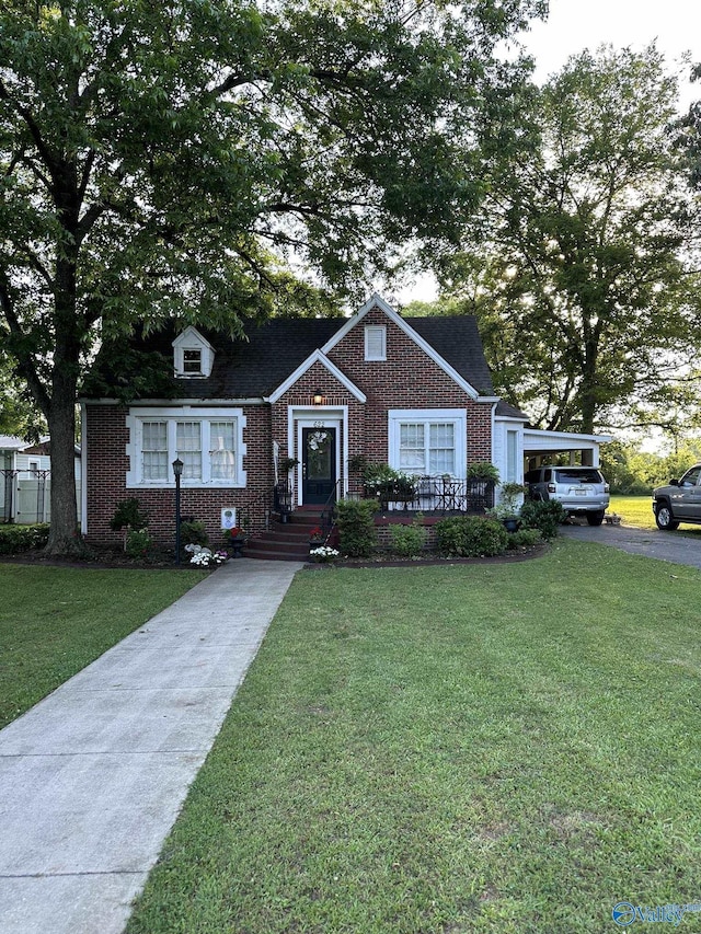 view of front of property with aphalt driveway, a front yard, and brick siding