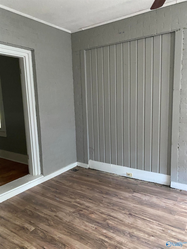 empty room featuring dark wood-type flooring and ornamental molding