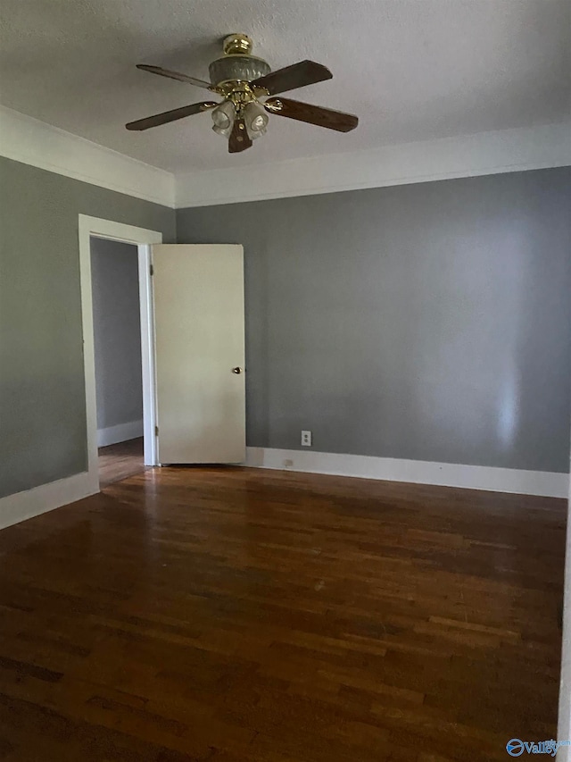 spare room featuring dark wood-type flooring, ceiling fan, and a textured ceiling