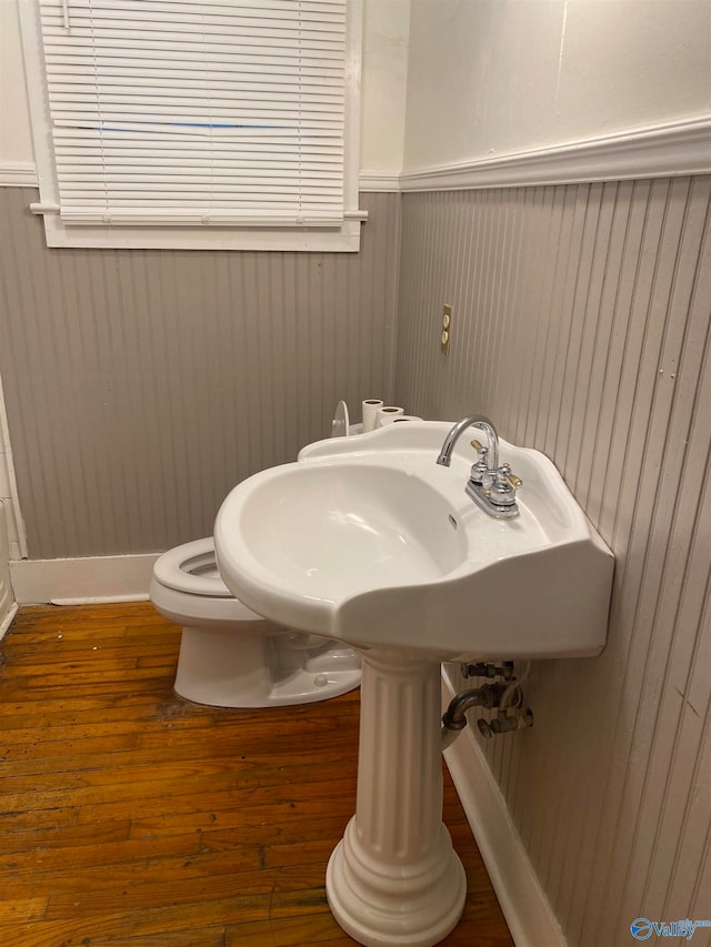 bathroom featuring toilet, wooden walls, and hardwood / wood-style flooring