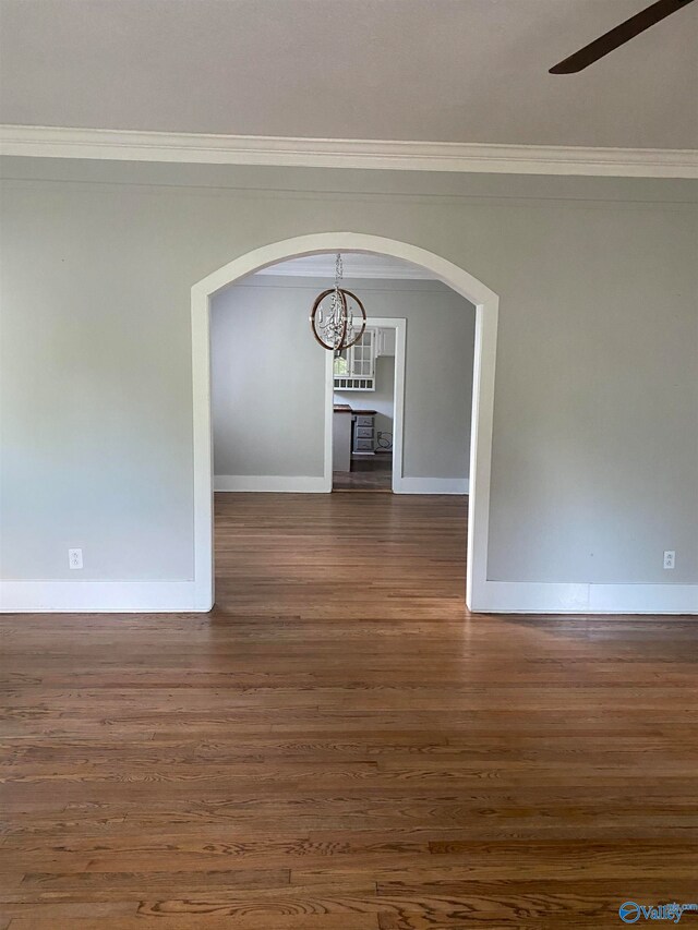 unfurnished dining area featuring ornamental molding, ceiling fan with notable chandelier, and dark wood-type flooring