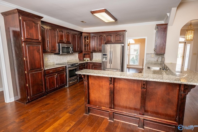 kitchen featuring ornamental molding, a sink, stainless steel appliances, arched walkways, and a peninsula