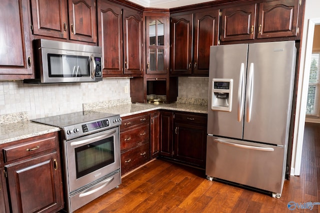 kitchen with dark wood-style floors, decorative backsplash, appliances with stainless steel finishes, and light stone counters