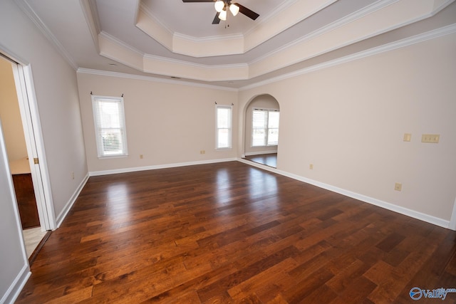 unfurnished room with arched walkways, plenty of natural light, dark wood finished floors, and a raised ceiling