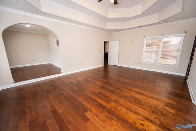 spare room with baseboards, ceiling fan, a tray ceiling, hardwood / wood-style floors, and arched walkways