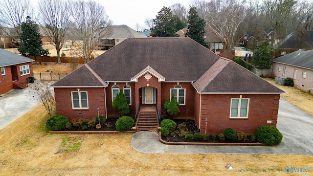 view of front facade featuring fence, brick siding, and a shingled roof