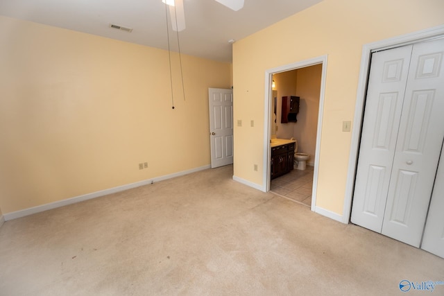 unfurnished bedroom featuring visible vents, light carpet, a closet, and connected bathroom