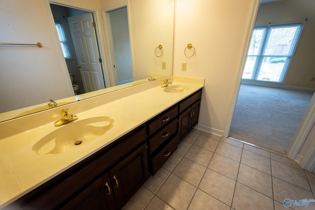 bathroom with tile patterned floors, double vanity, toilet, and a sink