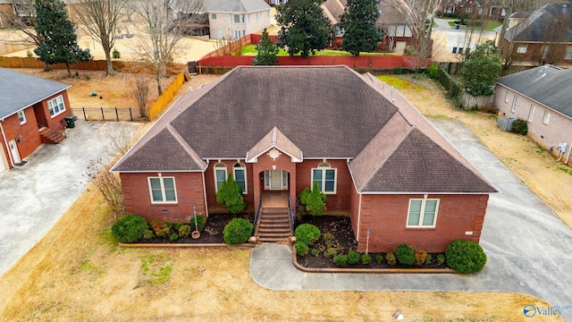 view of front of home with a residential view, brick siding, and fence