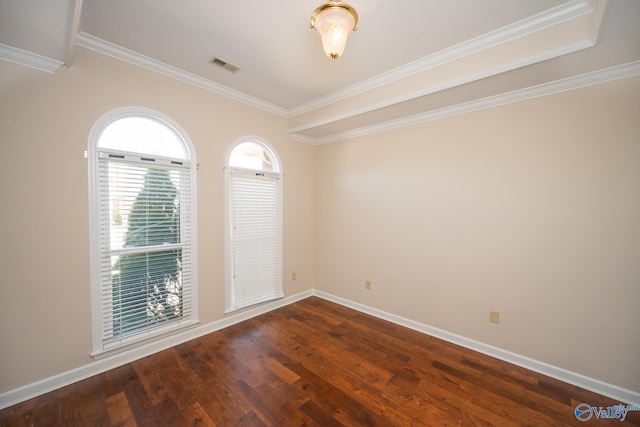 empty room with crown molding, wood finished floors, visible vents, and baseboards