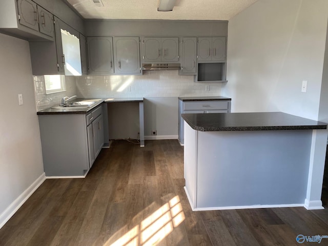 kitchen with kitchen peninsula, gray cabinets, sink, and dark hardwood / wood-style flooring