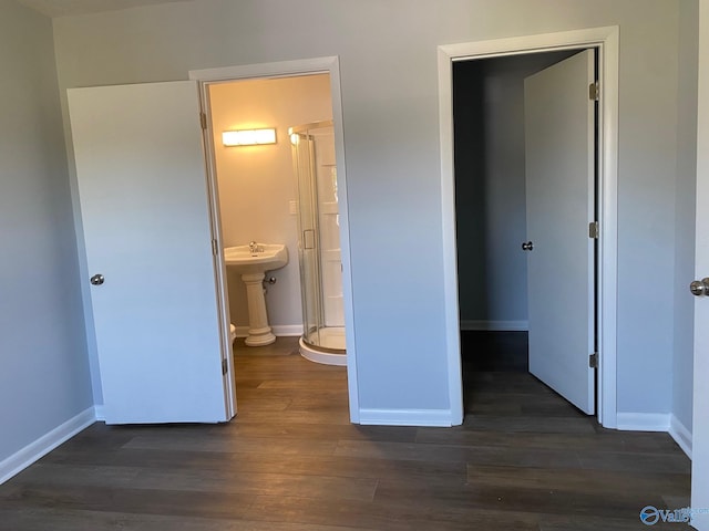 unfurnished bedroom featuring dark wood-type flooring, sink, and ensuite bath