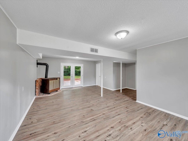 2612 Valley Brook Dr, Huntsville, AL 35811 - unfurnished living room featuring a wood stove, french doors, wood finished floors, and a textured ceiling