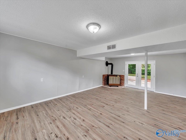 2612 Valley Brook Dr, Huntsville, AL 35811 - basement featuring wood finished floors, a textured ceiling, french doors, a wood stove, and heating unit