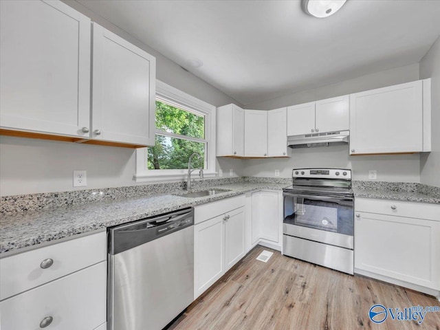 2612 Valley Brook Dr, Huntsville, AL 35811 - kitchen with stainless steel appliances, under cabinet range hood, light wood-style flooring, white cabinets, and light stone countertops