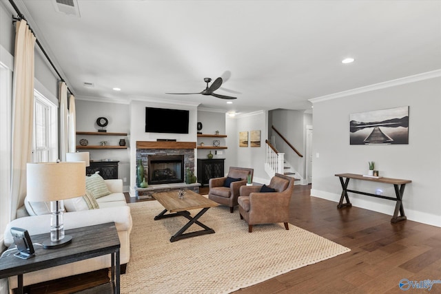 living area featuring visible vents, ornamental molding, dark wood-style flooring, stairs, and a fireplace