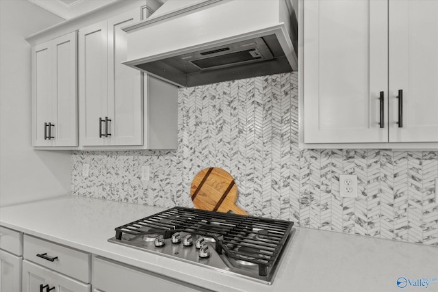 kitchen featuring stainless steel gas cooktop, tasteful backsplash, light countertops, custom range hood, and white cabinetry