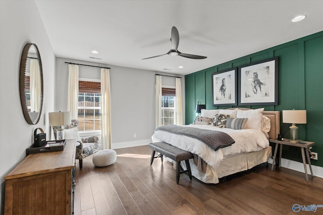 bedroom with dark wood-style flooring, visible vents, and a decorative wall